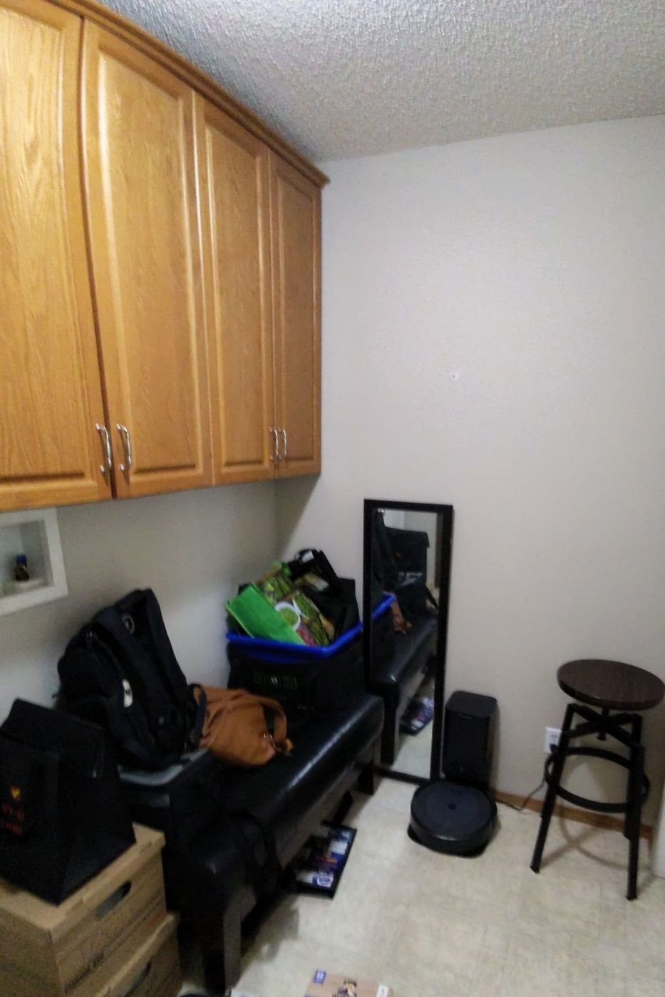 Another angle of the mudroom showing the closet with open doors, a black stool, and various items stacked on the floor and bench in Calgary | Kavaleer Renovations