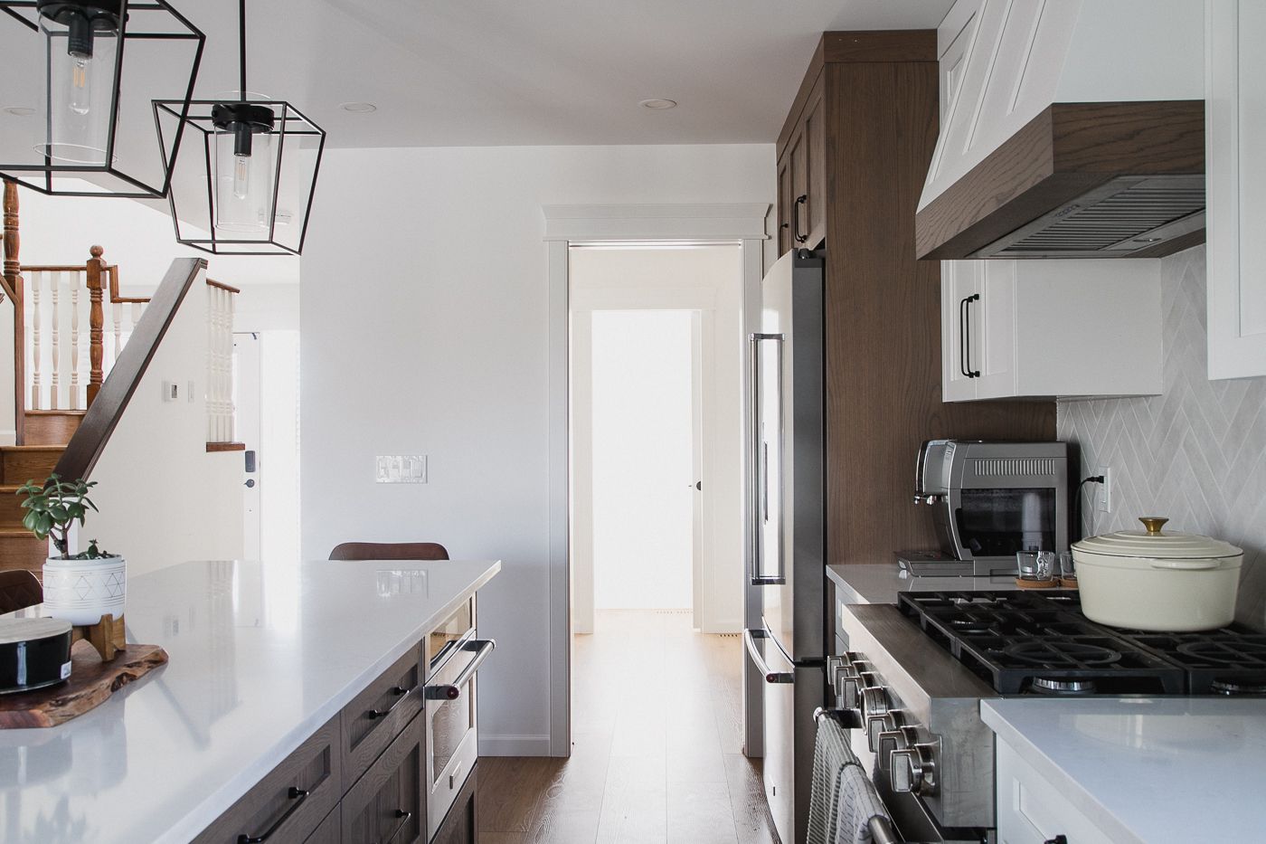 View from kitchen island toward hallway with wood floors and stair rail. in Calgary | Kavaleer Renovations