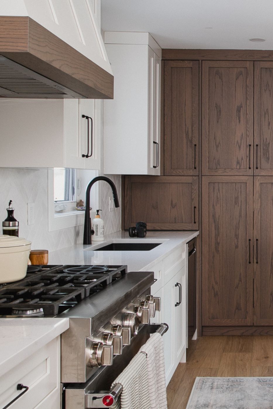 Stainless steel oven with striped tea towels and wood cabinetry. in Calgary | Kavaleer Renovations
